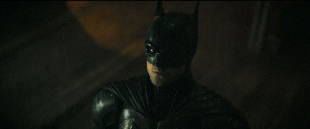 Batman, in his black attire, half disappears into darkness.