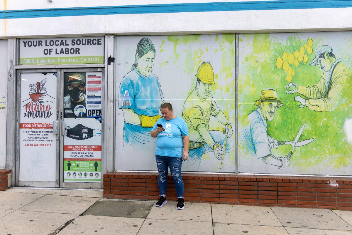 A woman stands in front of a storefront mural that includes gardeners.