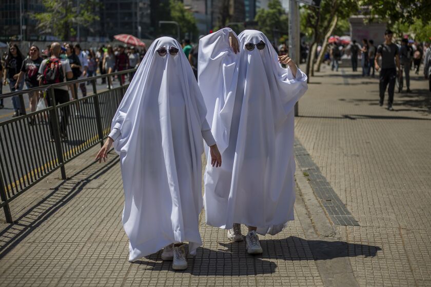 A couple of persons disguised as ghosts. After three years of absence, zombies and horrible creatures once again marched through the streets of Santiago de Chile on October 15, 2022. Zombie Walk Chile, a huge Halloween costume party, attracted a large number of people and even entire families participated. (Photo by Claudio Abarca Sandoval/NurPhoto via Getty Images)