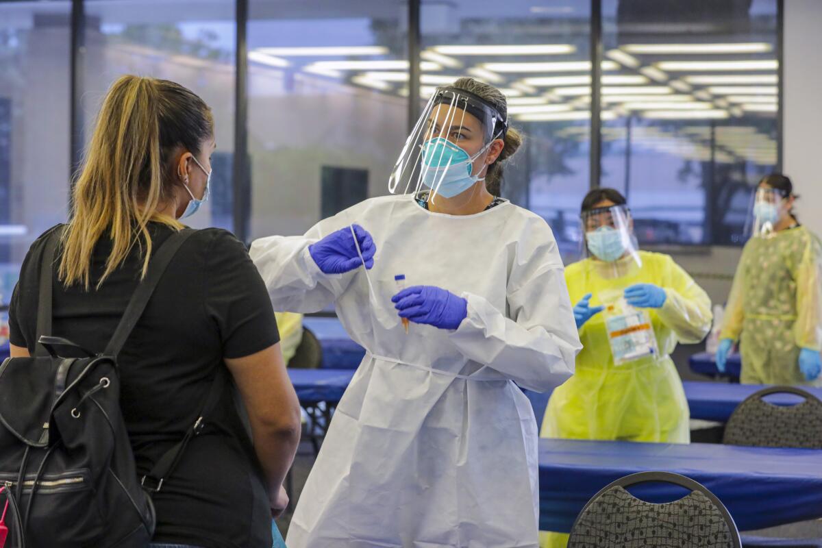 Elizabeth McKinnon tells Glenda Guerra how to self-swab for a COVID test at the Ontario Convention Center.