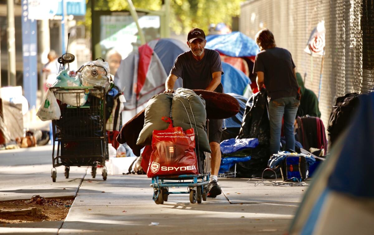 Homeless people pack up their belongings along First Street between Broadway and Spring Street during a cleanup Monday morning. The area targeted the sidewalk in front of a fenced-in empty lot next to a portion of Grand Park used for parking during scheduled events.