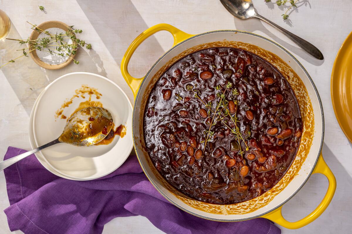 A pot with yellow handles, filled with baked beans, seen from above.