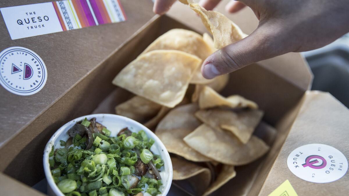 The Parker white queso with kale, griddled red onions, garlic, slow-roasted pork belly and scallions, served up with tortilla chips on the Queso Truck.