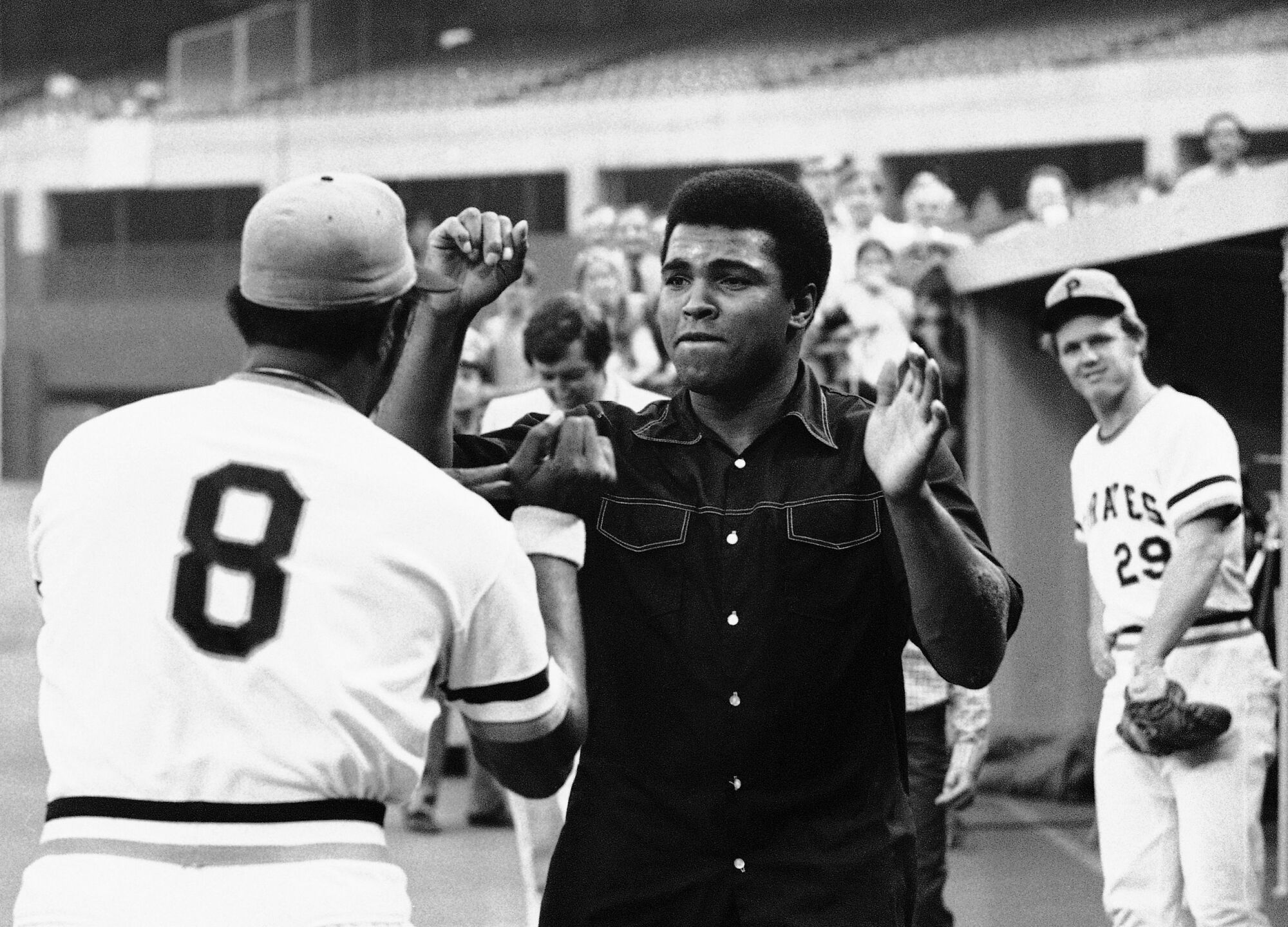 Muhammad Ali clowns with Willie Stargell on a baseball field.