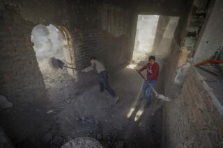 Men remove rubble for a gutted building