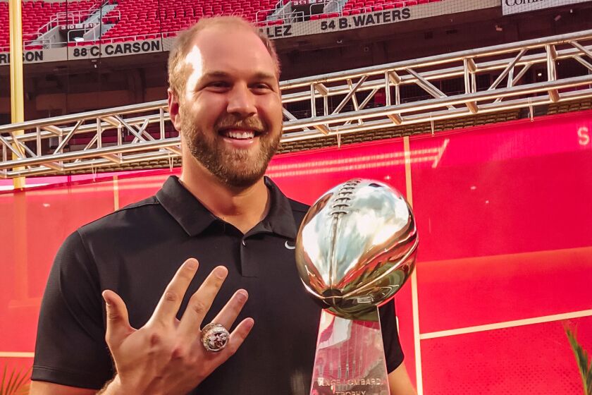 Mitchell Schwartz shows his championship ring as hje poses with the Vince Lombardi Trophy.