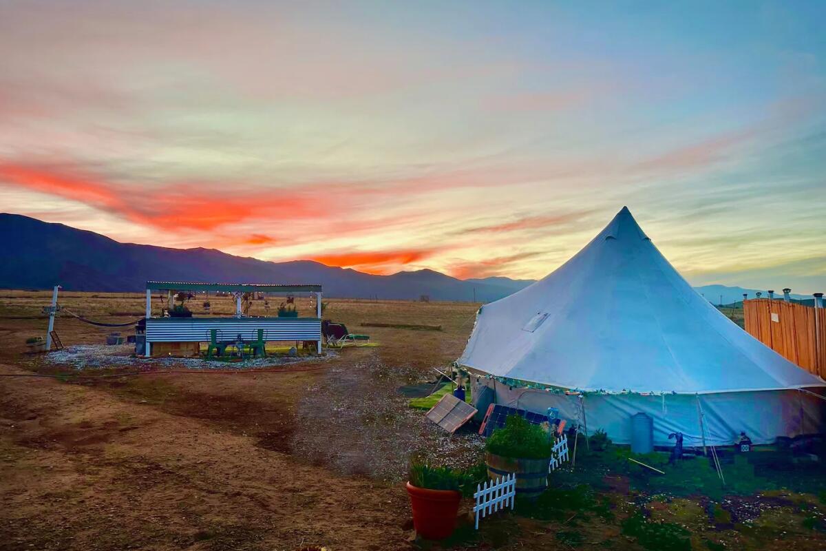A tent on the grounds at Cuyama Oaks Ranch, with a sunset beyond.