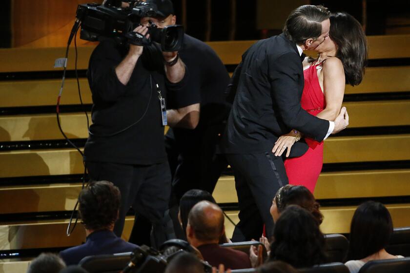Actress Julia Louis-Dreyfus is kissed by actor Bryan Cranston during the Emmy Awards at Nokia Theatre L.A. LIVE.