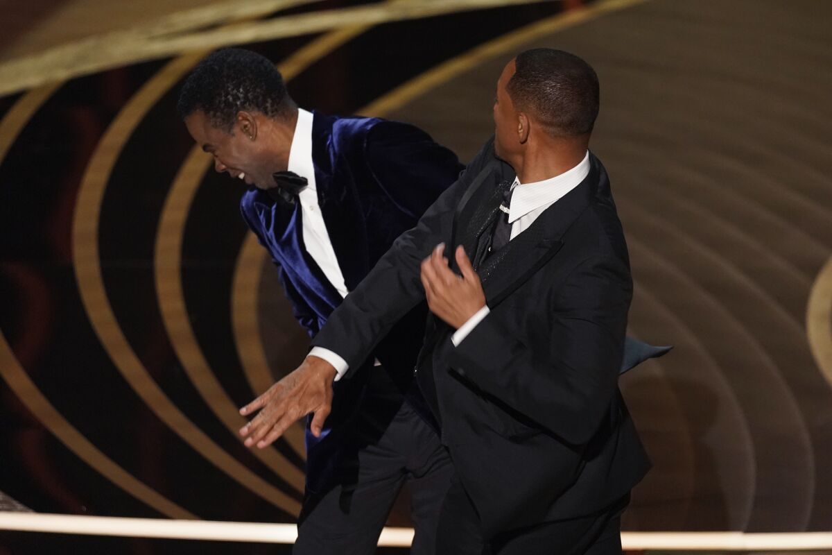 FILE - Will Smith, right, hits presenter Chris Rock on stage while presenting the award for best documentary feature at the Oscars on Sunday, March 27, 2022, at the Dolby Theatre in Los Angeles. On Friday, April 1, The Associated Press reported on stories circulating online incorrectly claiming a photo shows Rock wearing a pad on his cheek during the incident at the Oscars where Smith slapped him. (AP Photo/Chris Pizzello, File)