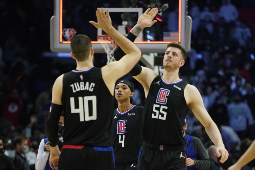 Los Angeles Clippers guard Brandon Boston Jr. (4) watches as center Ivica Zubac (40) and center Isaiah Hartenstein (55) celebrate after a 114-111 win over the Boston Celtics in an NBA basketball game in Los Angeles, Wednesday, Dec. 8, 2021. (AP Photo/Ashley Landis)