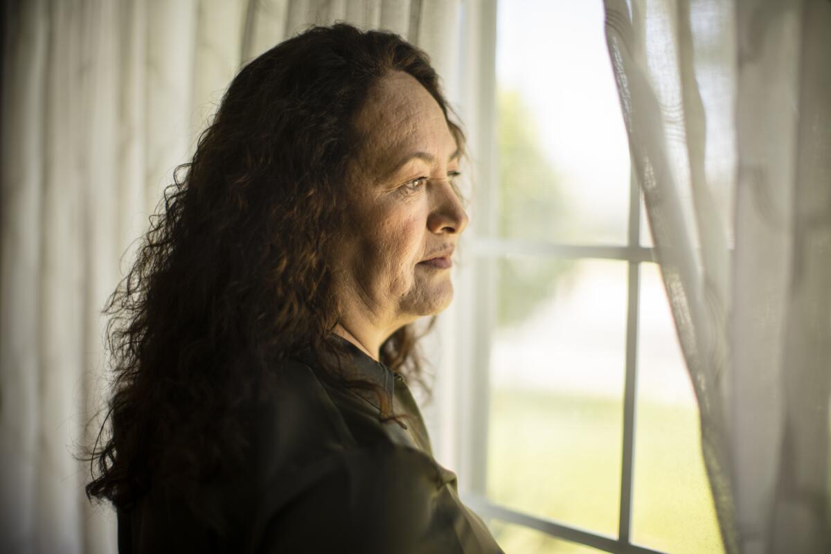 A woman stands at a window.