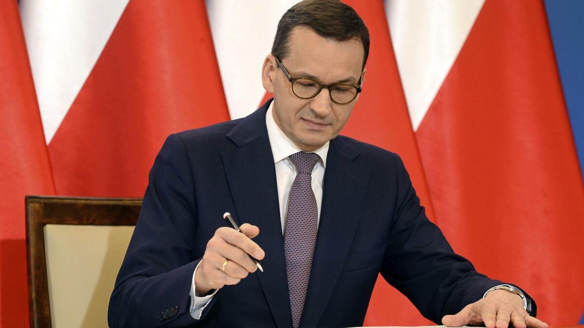 Polish Prime Minister Mateusz Morawiecki signs an agreement between Poland and Israel.