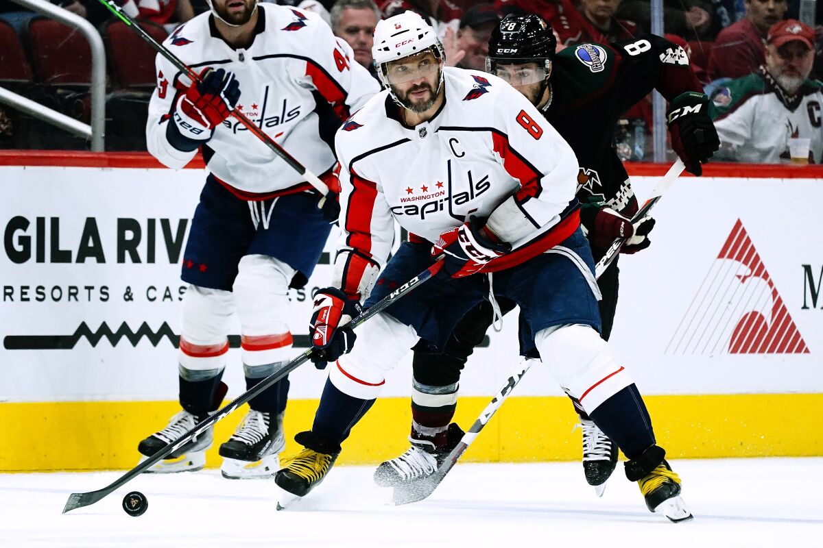 Washington Capitals left wing Alex Ovechkin (8) skates with the puck in front of Arizona Coyotes center Nick Schmaltz, right, during the second period of an NHL hockey game Friday, April 22, 2022, in Glendale, Ariz. (AP Photo/Ross D. Franklin)
