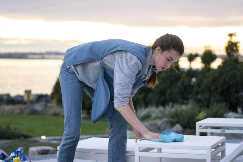 A woman bends to scrub outdoor furniture.