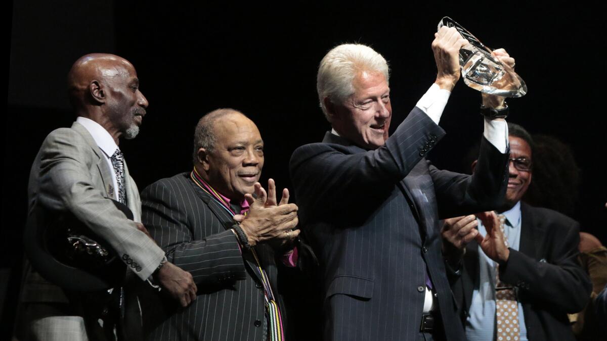 Former President Bill Clinton receives an award and is flanked by Thelonious Monk Jr., left, Quincy Jones and Herbie Hancock.
