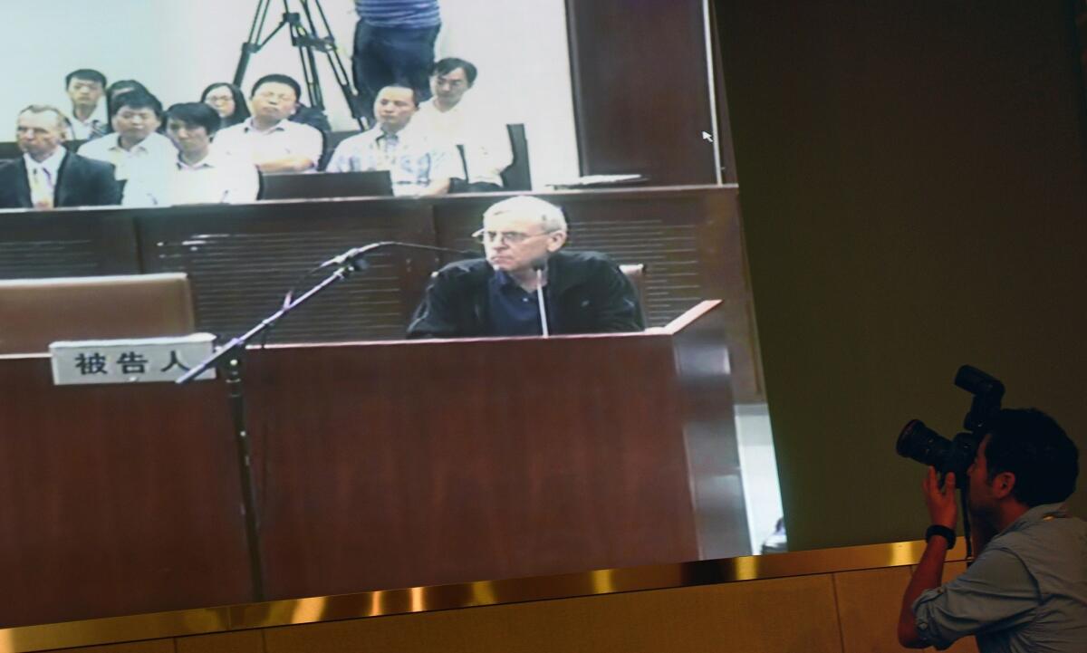 A TV screen shows the trial of British investigator Peter Humphrey and his wife at the Shanghai Intermediate Court on Aug. 8.