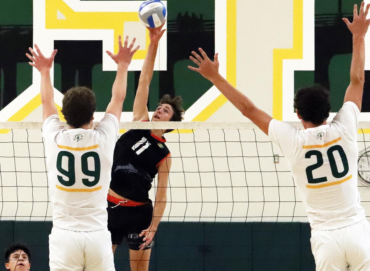 Huntington Beach's Logan Hutnick (11) tries to spike the ball past Mira Costa's Alex Heins (99) and Grayson Bradford (20).