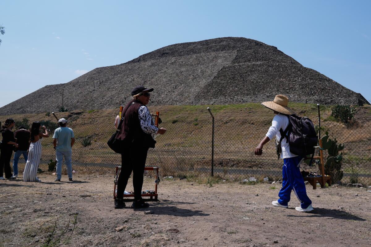Handicraft vendors and tourists stand outside the Teotihuacán pyramids