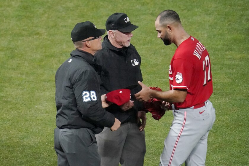 Cincinnati Reds' relief pitcher Art Warren (77) gets a glove and cap check for sticky substances from umpires, including second base umpire Jim Wolf, left, after pitching against the Minnesota Twins in a baseball game, Monday, June 21, 2021, in Minneapolis. (AP Photo/Jim Mone)