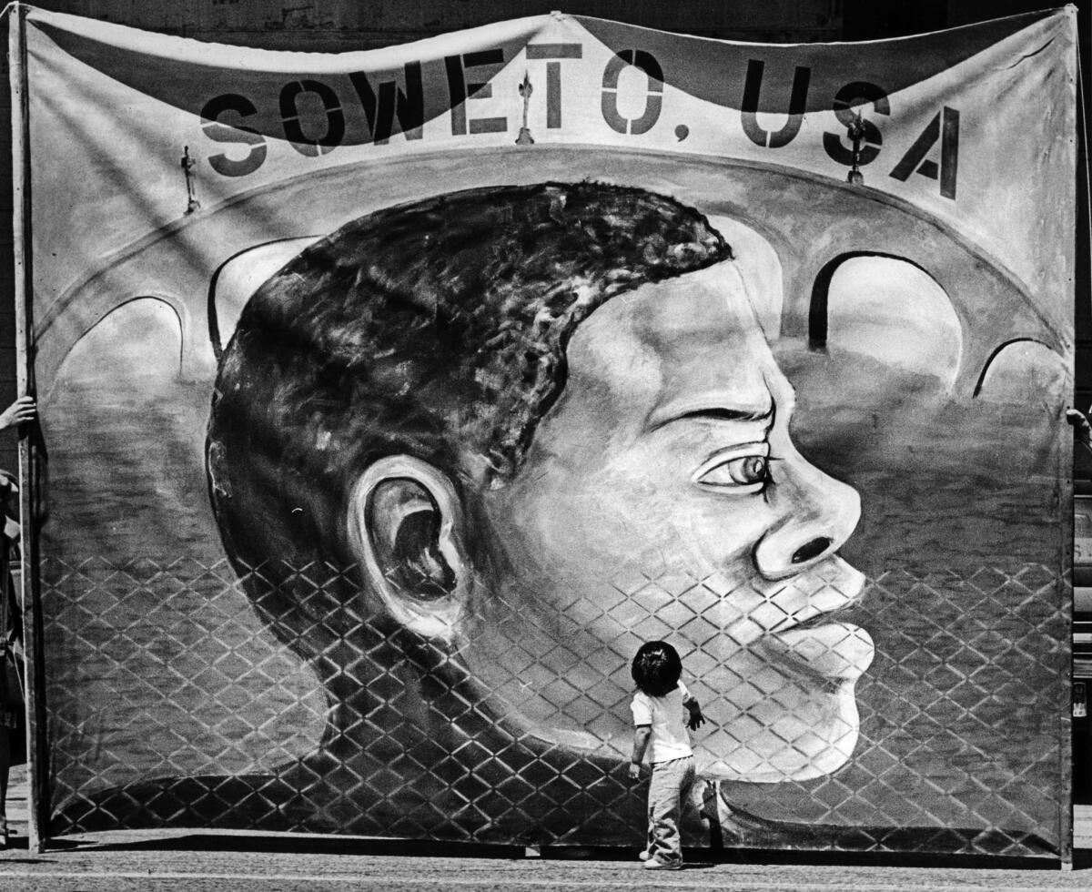 June 15, 1987: A child looks at a banner displayed by protesters outside the encampment. Activists said the city needed more low-income housing, not campgrounds for the homeless.