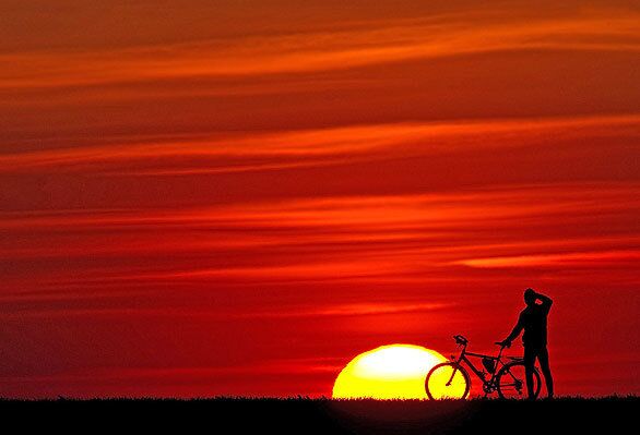 A cyclist admires a sunset enhanced by volcanic ash.