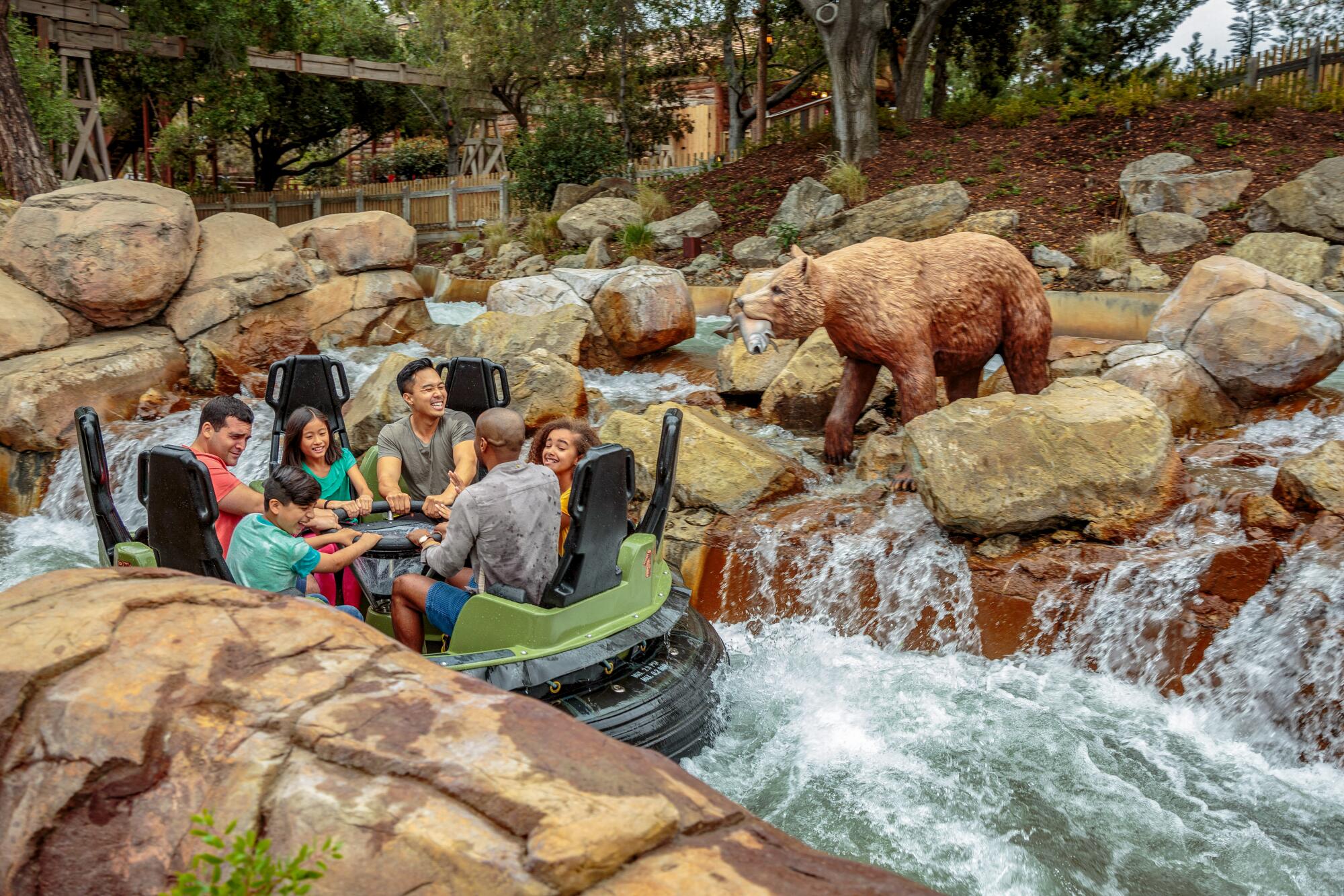 Animatronic bears loom over theme park-goers on a boat traveling among rocks and rapids