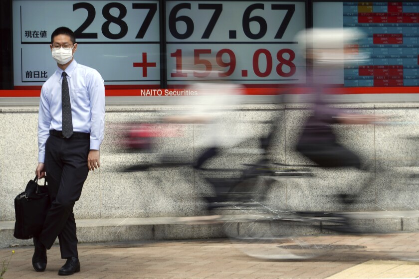 A man wearing a protective mask stands in front of an electronic stock board showing Japan's Nikkei 225 index at a securities firm Wednesday, May 12, 2021, in Tokyo. Asian stock markets retreated Wednesday as investors looked ahead to U.S. data they worry will show inflation is picking up. (AP Photo/Eugene Hoshiko)