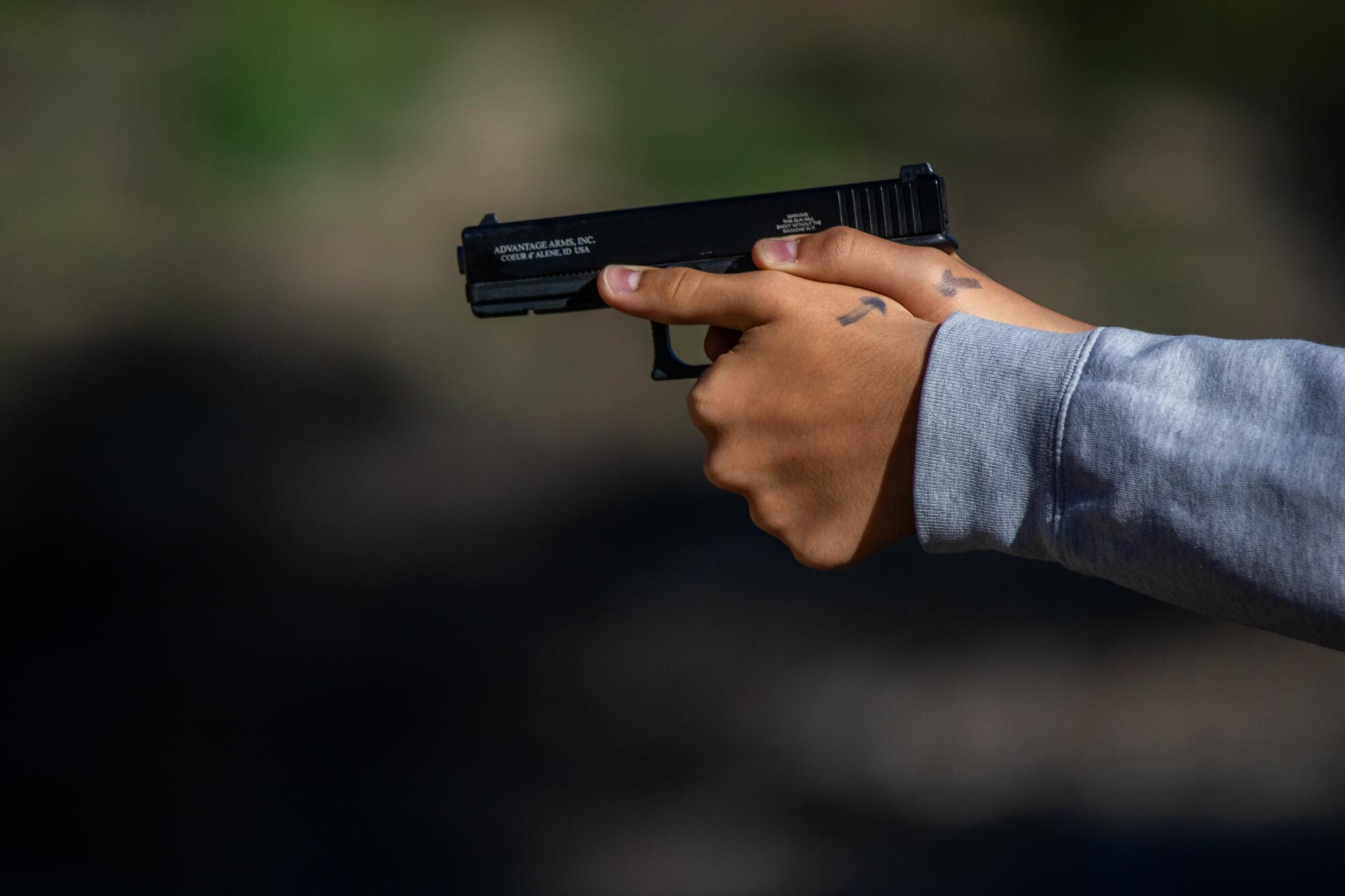 Two hands holding a black pistol at a gun range