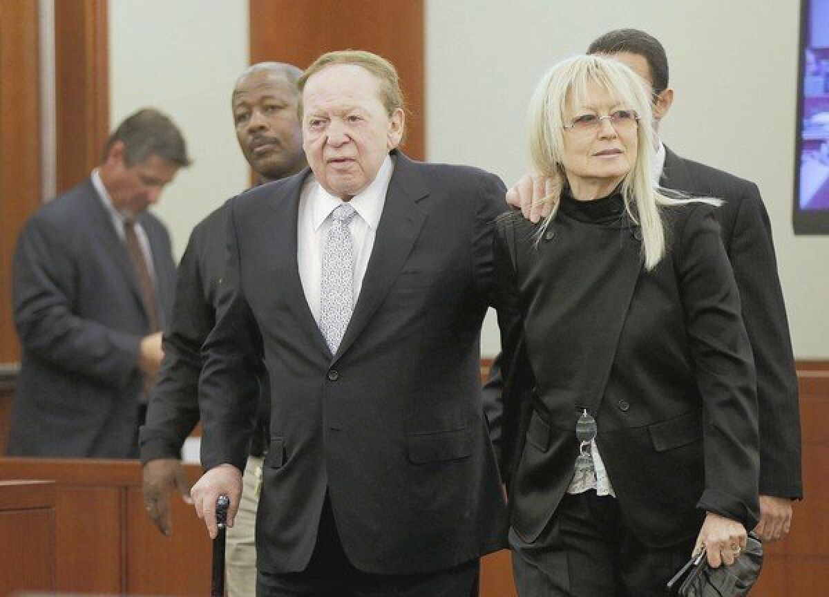 Las Vegas Sands Corp. Chief Executive Sheldon Adelson walks into court with his wife, Miriam, as he prepares to testify in a breach-of-contract case involving his company.
