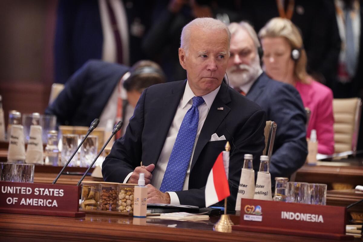 President Biden listens while sitting at a meeting of world leaders