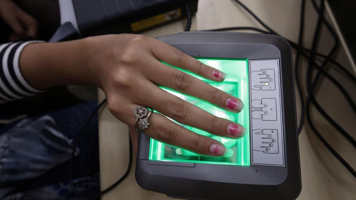 A woman gives her finger impressions for her Aadhaar card at a card enrollment center in Amritsar, India.