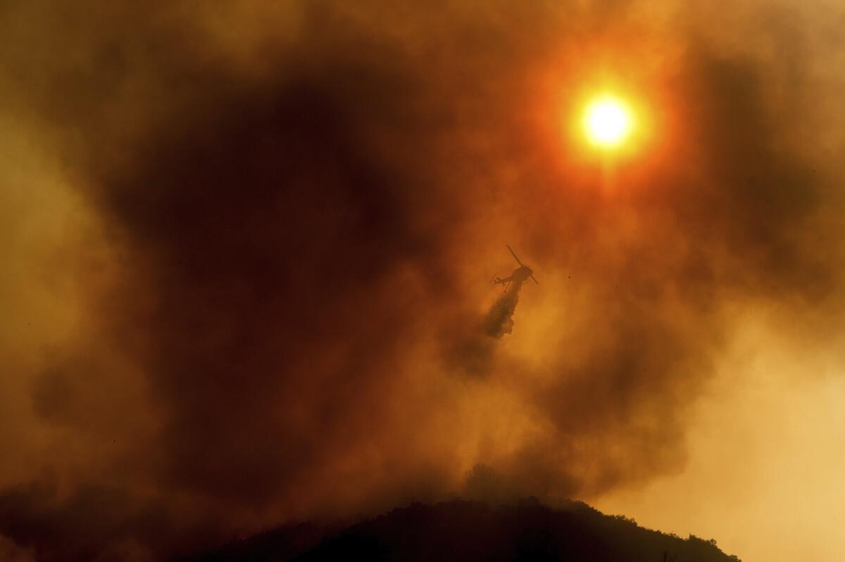 ARCHIVO - un helicóptero arroja agua mientras combate un incendio forestal en Salinas, California.