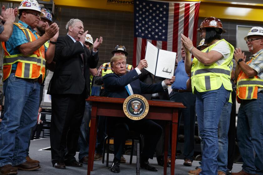 FILE - In this April 10, 2019, file photo, President Donald Trump holds up an executive order on energy and infrastructure after signing it at the International Union of Operating Engineers International Training and Education Center in Crosby, Texas. Attorneys general in 20 states and the District of Columbia sued the Trump administration on Tuesday, July 21, 2020, alleging that new federal rules undermine their ability to protect rivers, lakes and streams within their borders. President Trump in April 2019 issued an executive order directing the change that critics said could make it harder for states to block pipelines and other projects over concerns that they could impair water quality. (AP Photo/Evan Vucci, File)