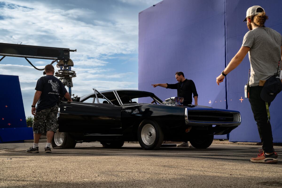 A film crew works around a hot rod on the set of "Fast X."
