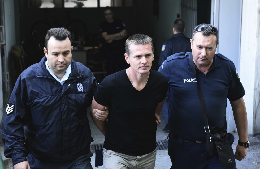 FILE - In this Oct.4, 2017 file photo, police officers escort Alexander Vinnik, center as they leave a courthouse at the northern Greek city of Thessaloniki. The Russian bitcoin expert at the center of a multi-country legal tussle was sentenced in Paris on Monday to five years in prison for money laundering and ordered to pay 100,000 in fines in a case of suspected cryptocurrency fraud. (AP Photo/Giannis Papanikos, File)