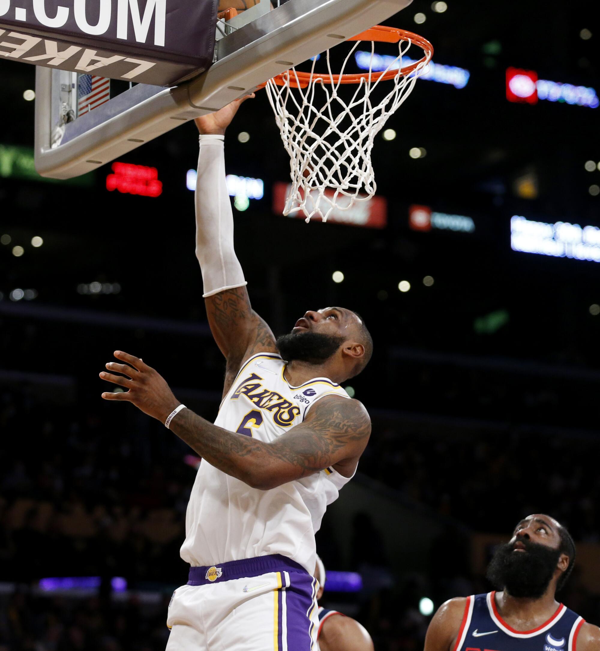 Lakers forward LeBron James scores in front of Brooklyn Nets guard James Harden in the first half.