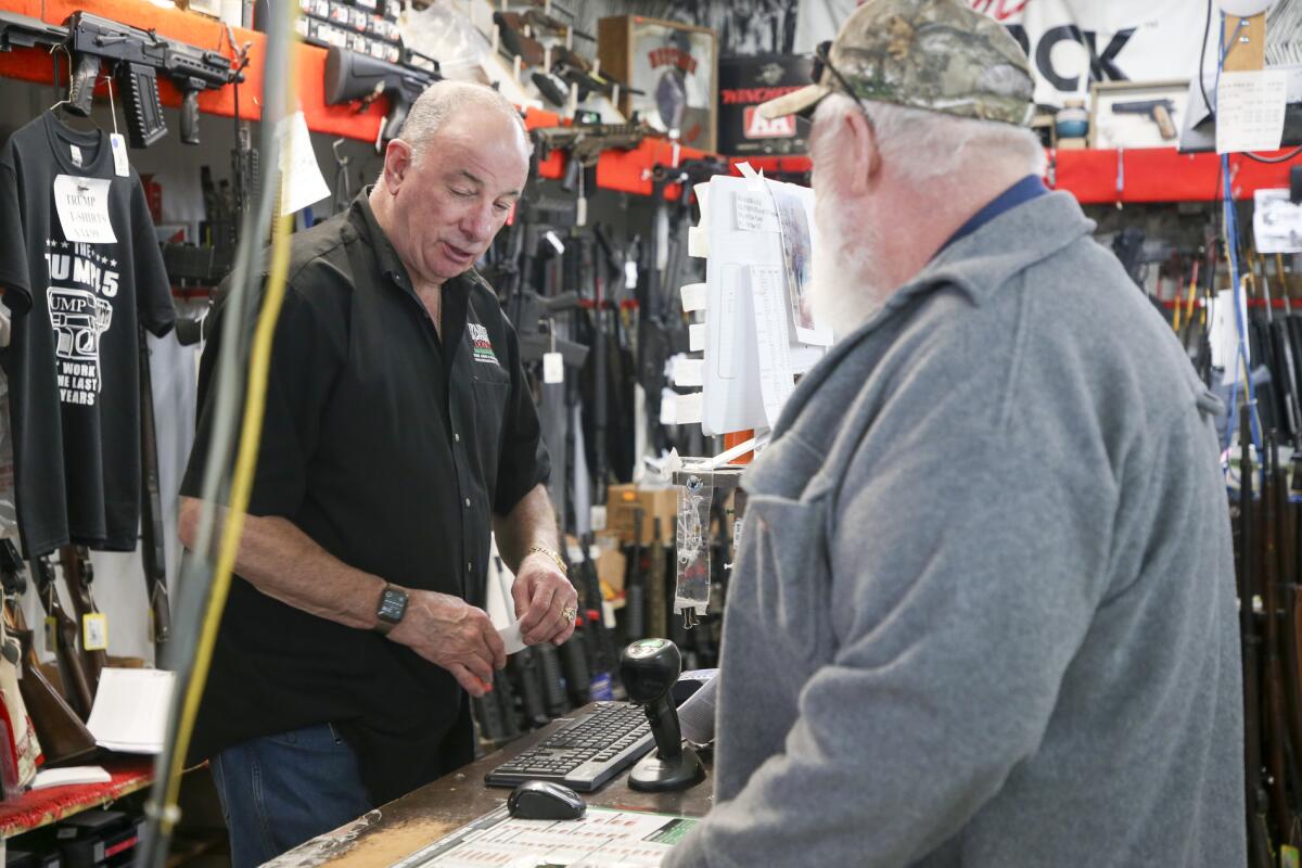 David Stone closes a sale with customer Bill Collins at a Tulsa, Okla., gun store.