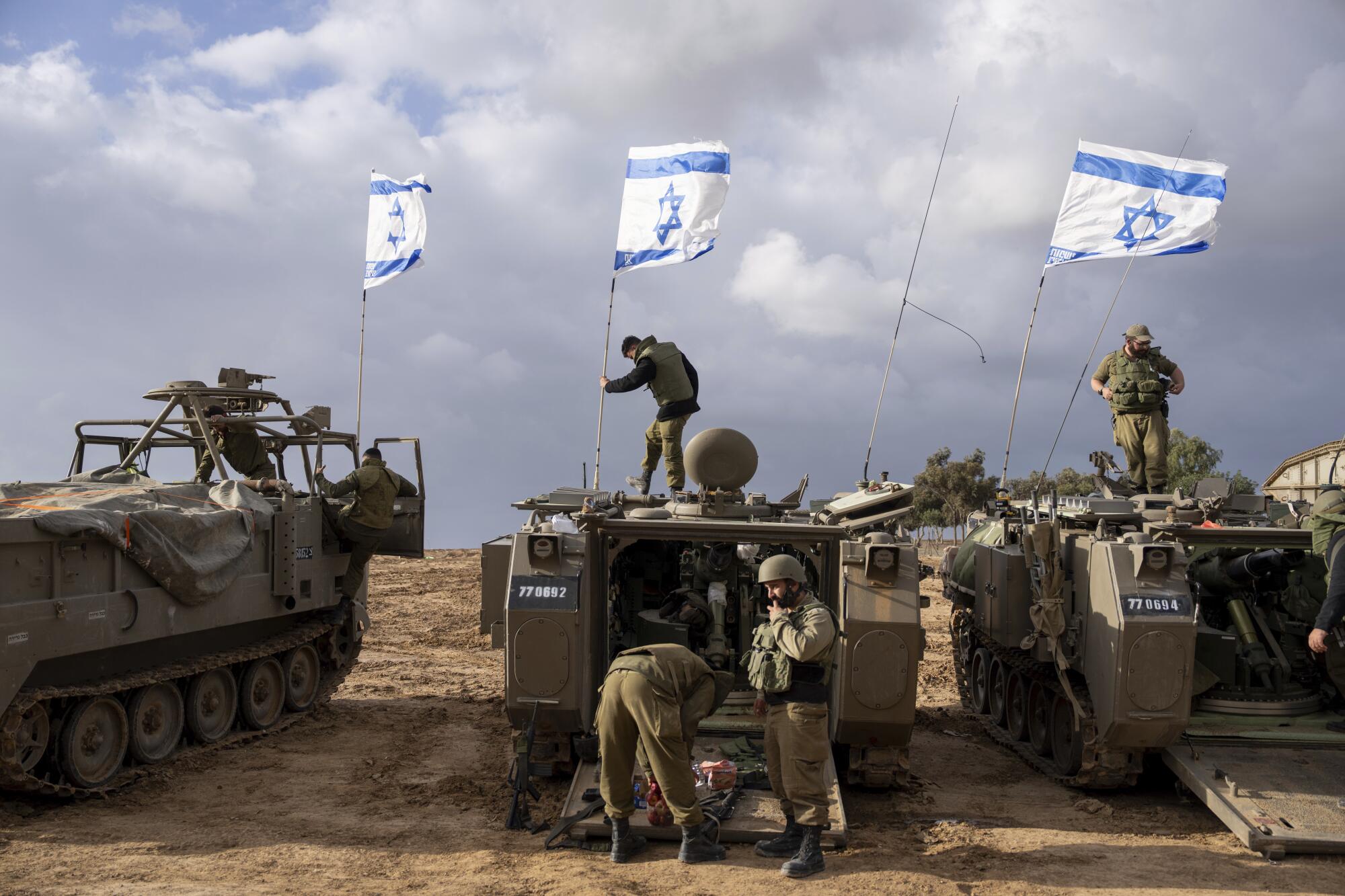 Israeli flags fly from several armored vehicles.