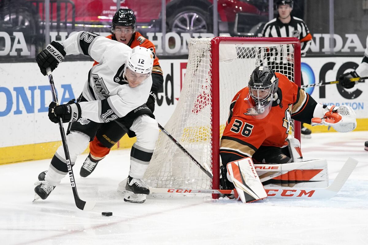 Los Angeles Kings center Trevor Moore, left, tries to get a shot past Anaheim Ducks goaltender John Gibson, right, as defenseman Haydn Fleury defends during the first period of an NHL hockey game Friday, April 30, 2021, in Anaheim, Calif. (AP Photo/Mark J. Terrill)
