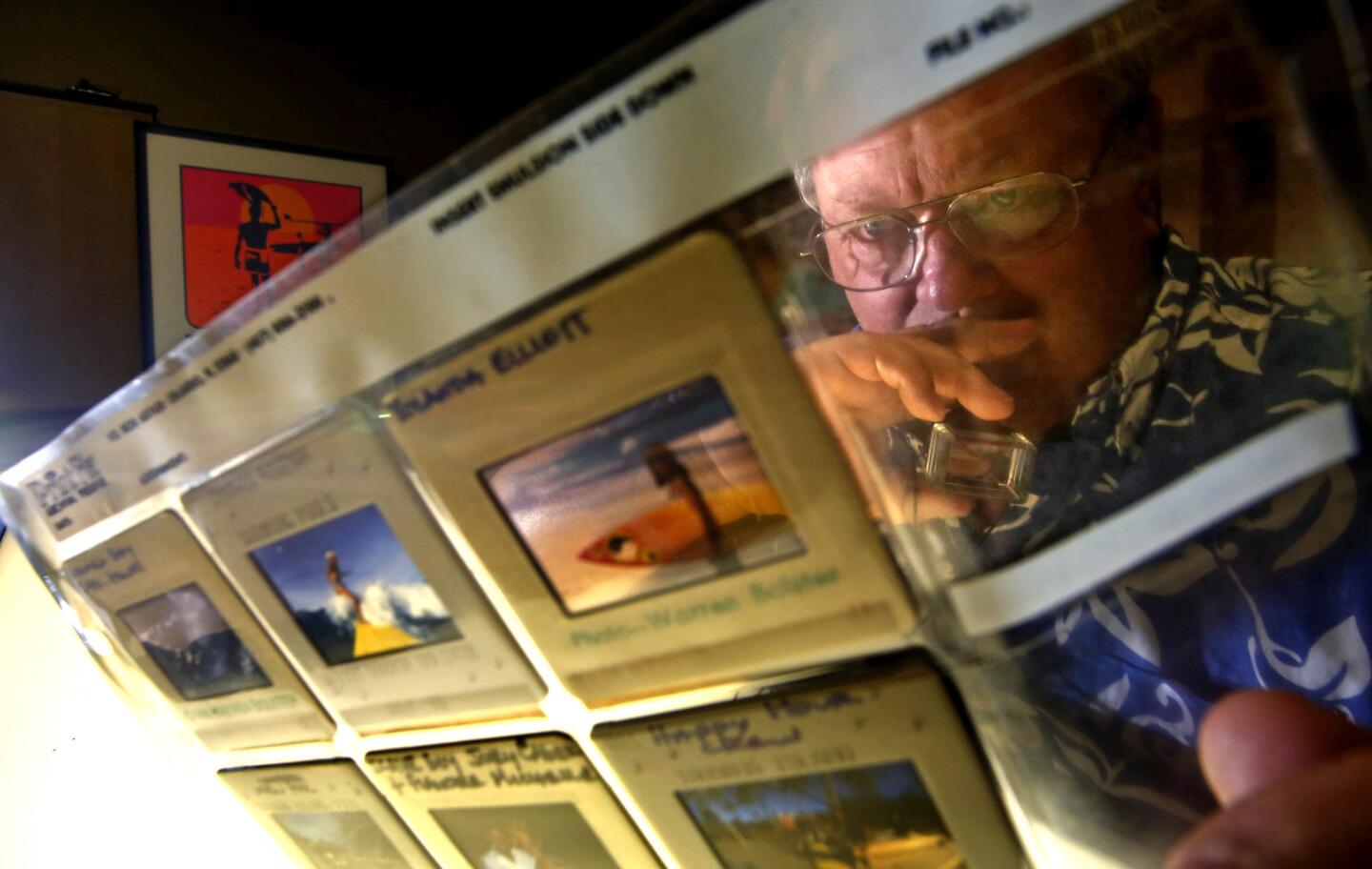 Steve Wilkings looks through Kodachrome slides by the late surf photographer Warren Bolster. Some of the 140 collections held by the center are encyclopedic -- thousands of photos of surfers hanging ten on longboards, dropping into steep pitches or shooting through curls.
