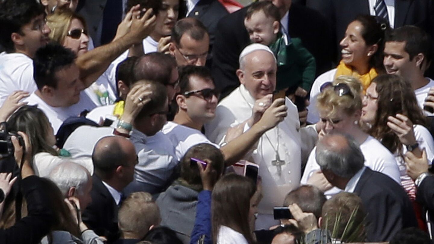 Pope Francis poses with faithful at the end of a Palm Sunday service in St. Peter's Square at the Vatican on April 13, 2014.