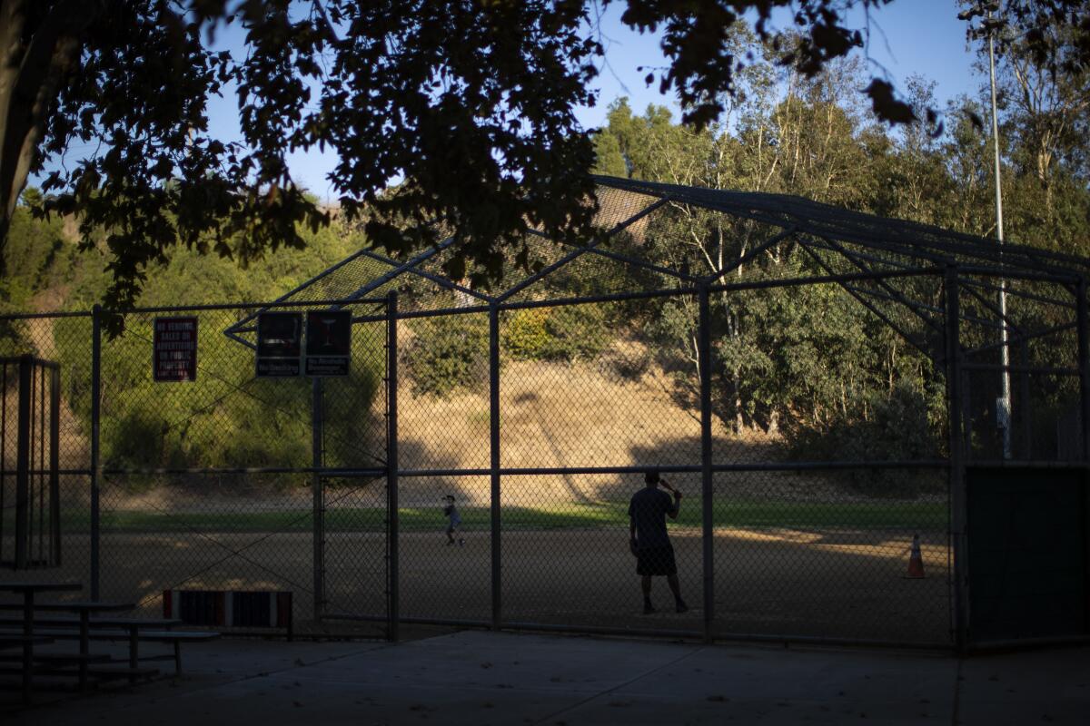 A father hits grounders to his son on the baseball field at Rose Hill Park.