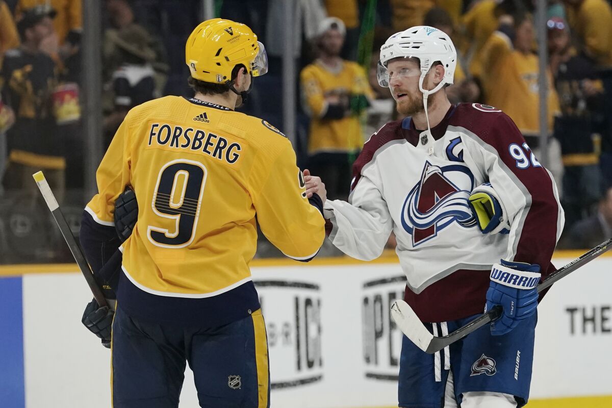 Colorado Avalanche left wing Gabriel Landeskog (92) shakes hands with Nashville Predators' Filip Forsberg (9) after Game 4 of an NHL hockey first-round playoff series Monday, May 9, 2022, in Nashville, Tenn. The Avalanche won 5-3 to sweep the series 4-0. (AP Photo/Mark Humphrey)