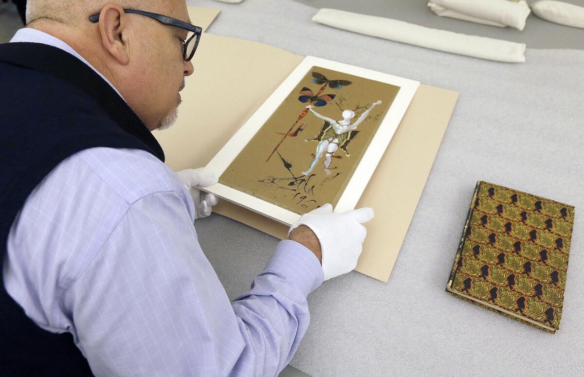 In this May 1, 2015 photo, Michael Labrie, director of collections and exhibitions at the Walt Disney Family Museum, looks at art work by Salvador Dali that was put on the cover of the 1961 Bal Chouinard program, in a collections room at the Disney museum in San Francisco. Besides his love of wholesome entertainment, Walt Disney also had an appreciation for the eccentric that led to a short-lived partnership and decades-long friendship with surrealistic artist Salvador Dali. (AP Photo/Jeff Chiu)