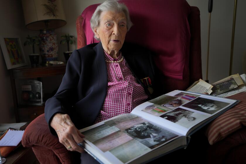 Christian Lamb who was a serving Wren at the time of D-Day, looks through a photograph album at her home in London, Thursday, April 11, 2024. D-Day, took place on June 6, 1944, the invasion of the beaches at Normandy in France by Alied forces during World War II.(AP Photo/Kirsty Wigglesworth)
