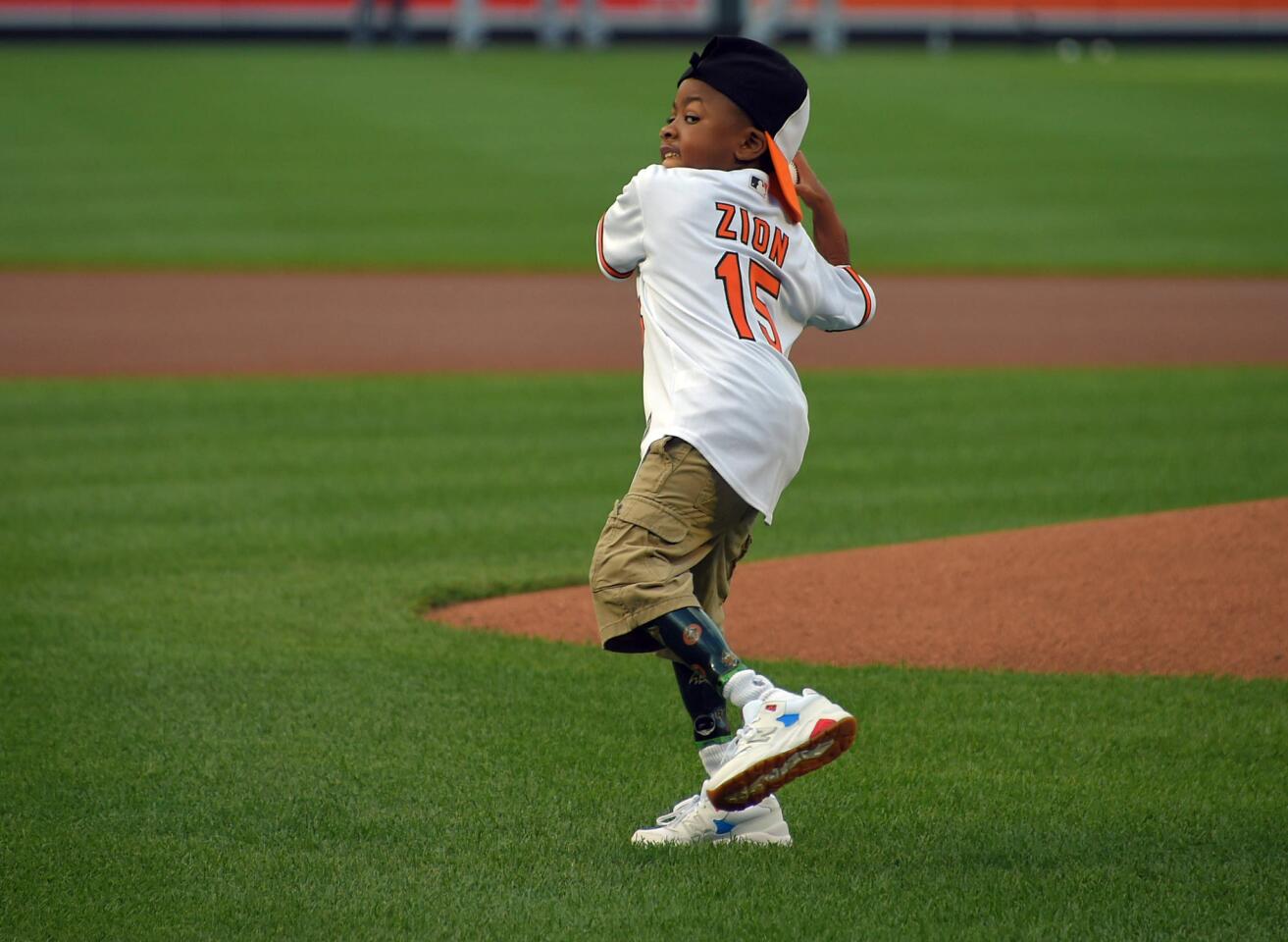 Nine-year-old Zion Harvey of Owings Mills, who has two transplanted hands, throws out the first pitch to Baltimore Orioles center fielder Adam Jones before the game between the Orioles and the Texas Rangers at Oriole Park at Camden Yards on Aug. 2, 2016.