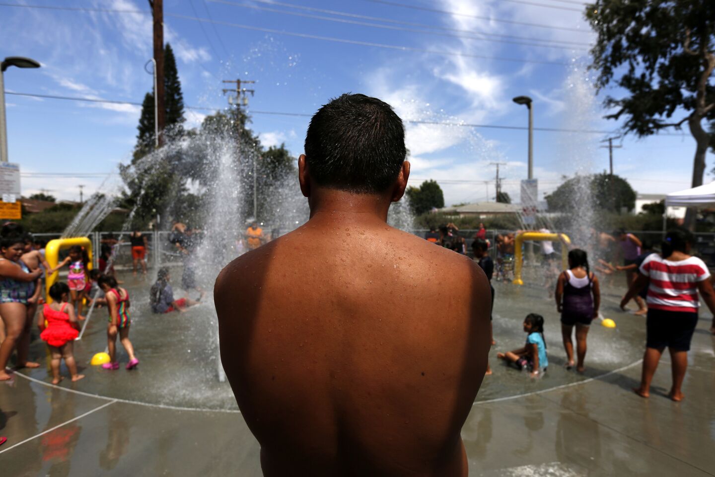People cool off in the spray pool at Lemon Park in Fullerton.