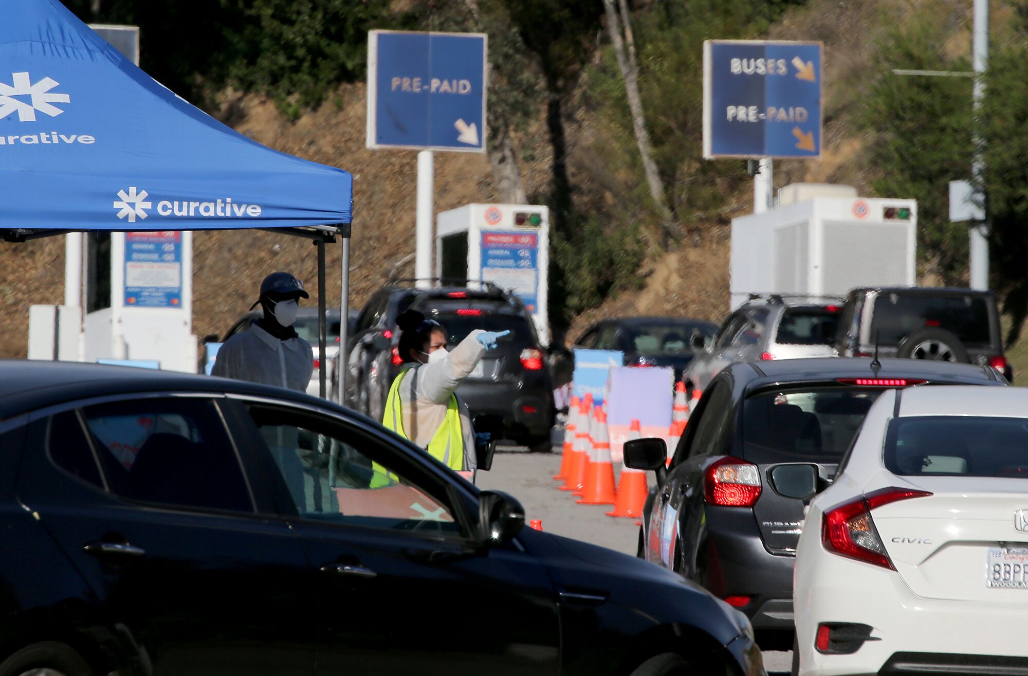 Drivers seeking COVID tests line up at a drive-though site in the parking lot of Dodger Stadium