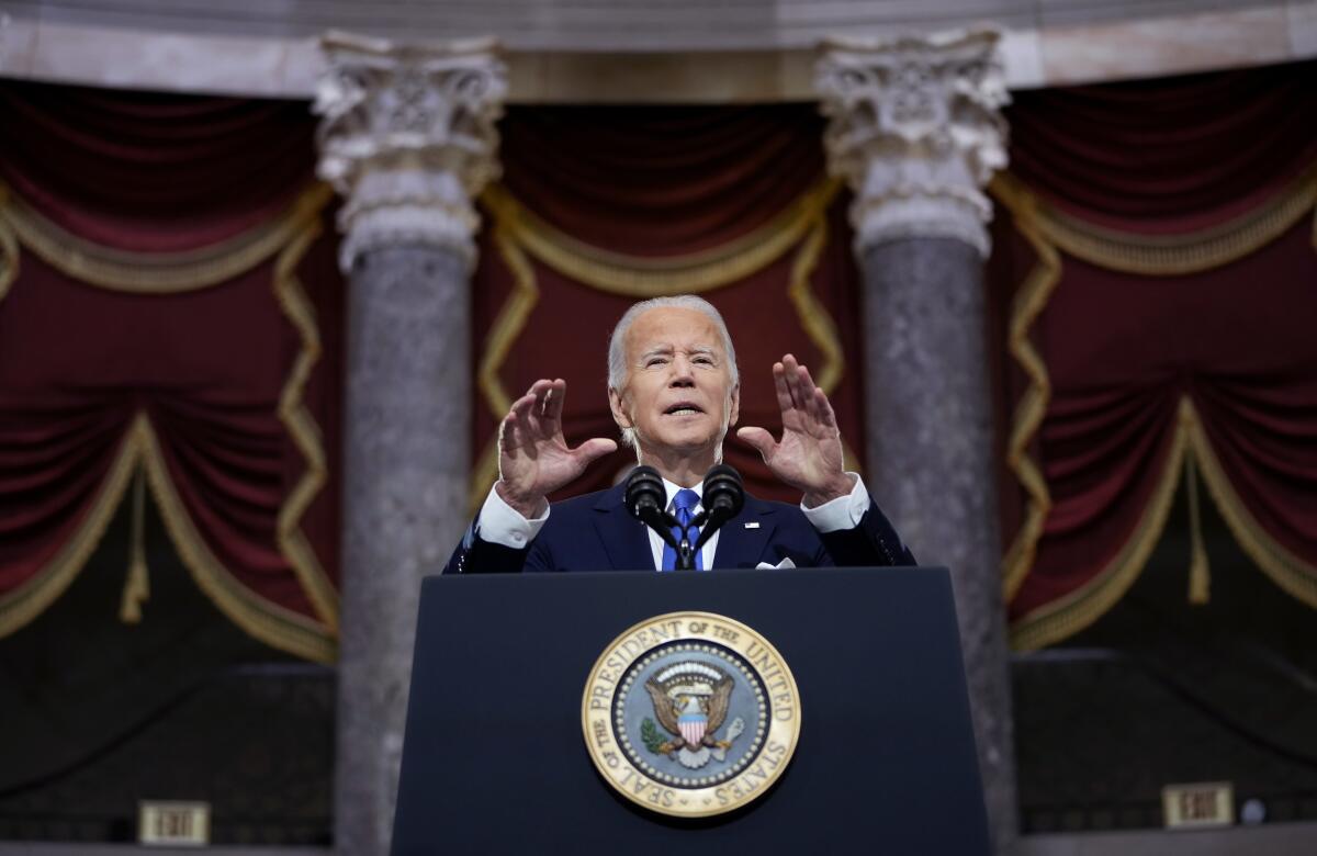 President Biden gestures  as he speaks from behind a lectern.