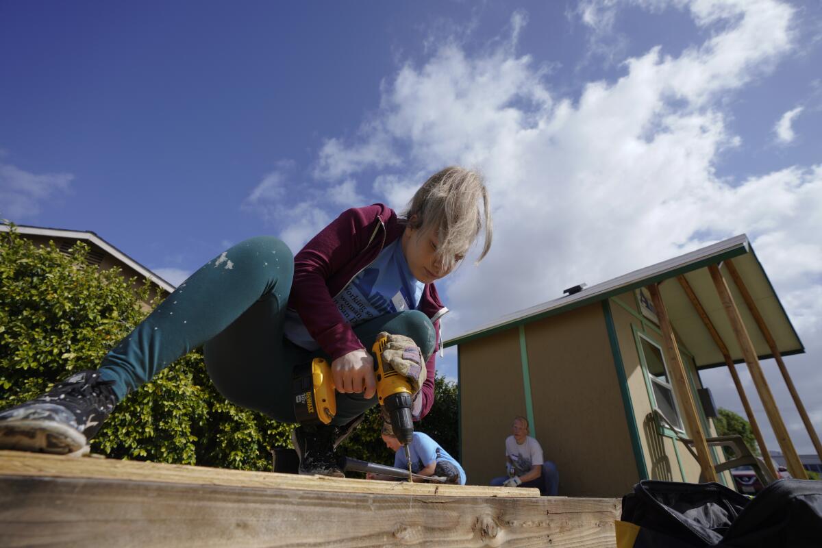 A woman drills a hole into lumber